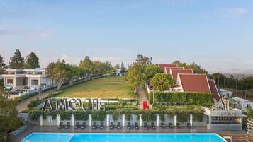 Un hotel con piscina, sillas de descanso y un letrero que dice 'Pool Bar'.