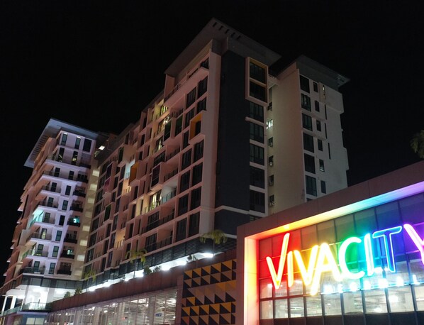 Un hôtel à plusieurs étages, doté de balcons et d’une enseigne lumineuse affichant le mot « VIVACITY ».
