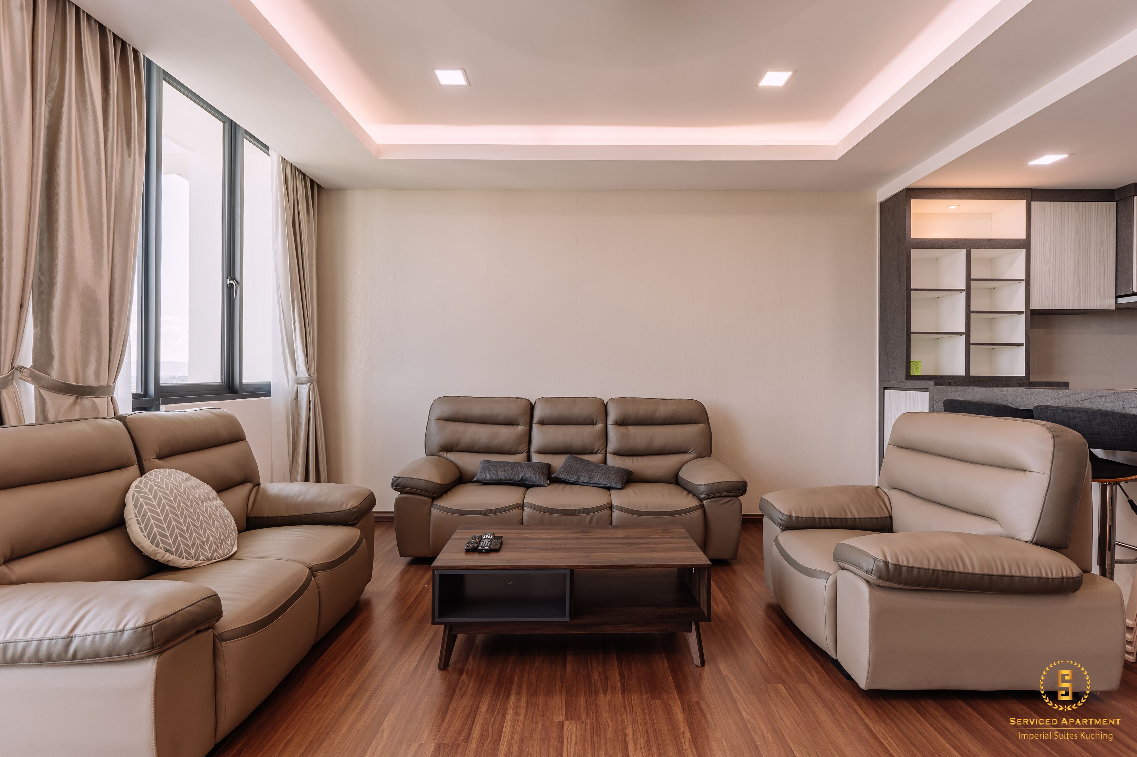 A modern living room with a sofa set, a coffee table, and a kitchen area in the background.