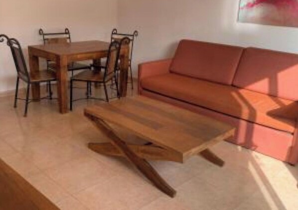 A living room with a wooden coffee table, a sofa, and a dining table with chairs.