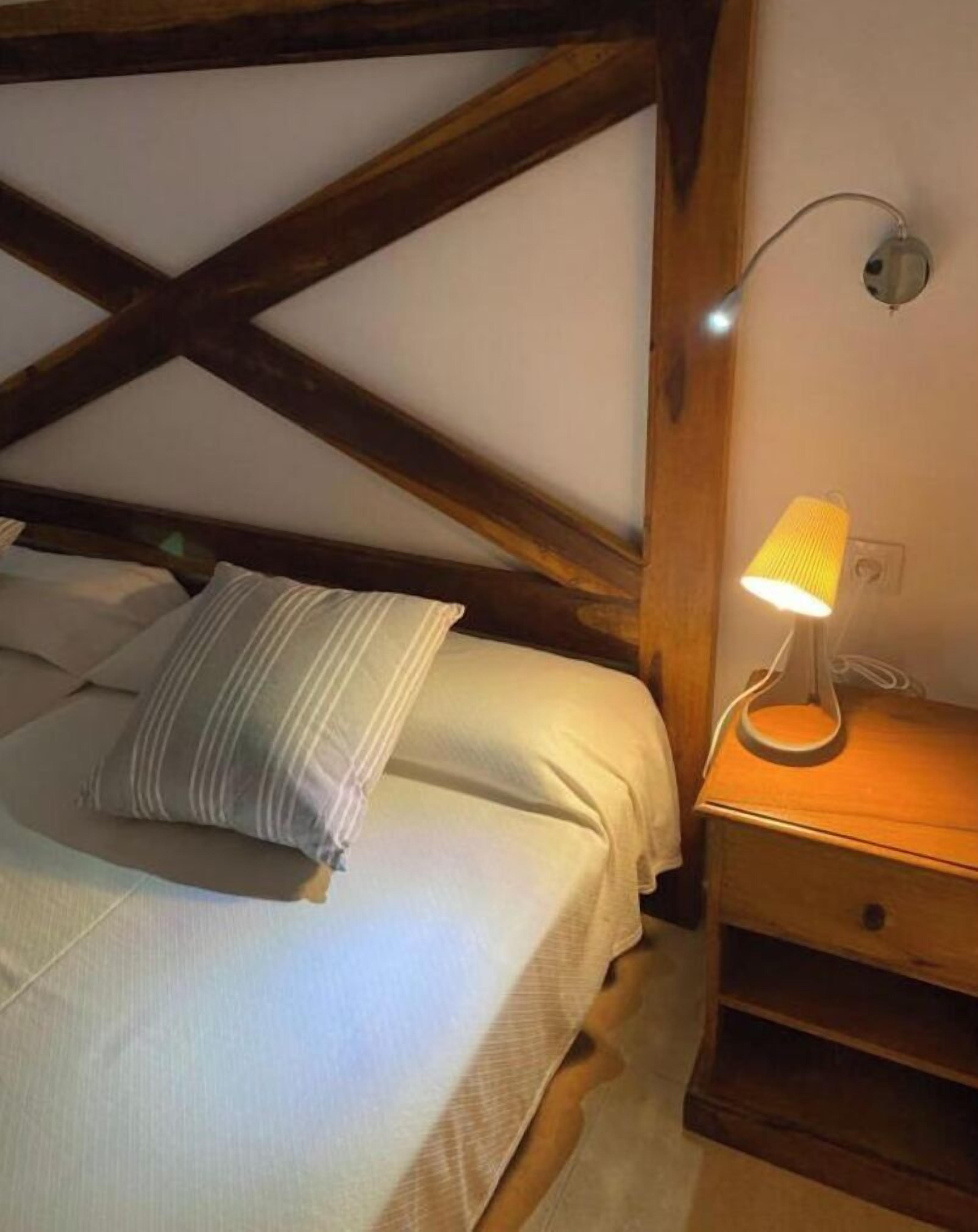 A bedroom with a bed, a bedside lamp, and a wooden headboard.