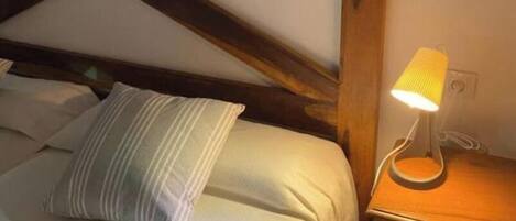 A bedroom with a bed, a bedside lamp, and a wooden headboard.
