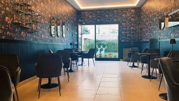 A modern interior with a floral wallpaper, multiple seating areas, and a view through a glass door.