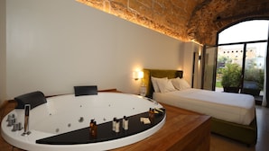 Una habitación moderna con una bañera grande, una cama y vistas de la ciudad a través de un amplio ventanal.