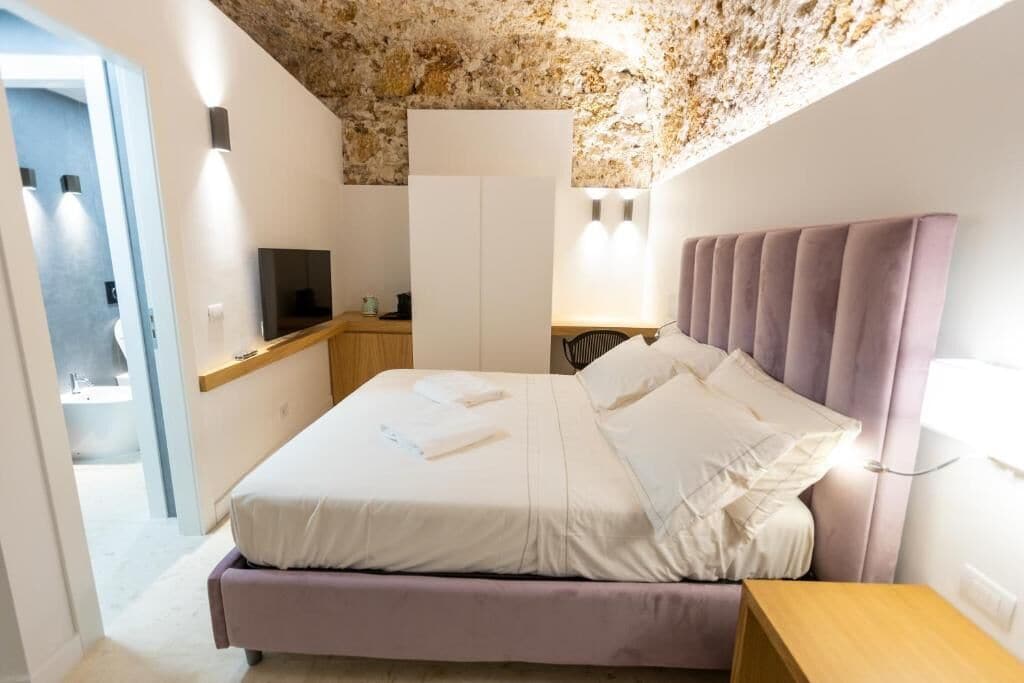 A bedroom with a bed, bedside table, and a TV.