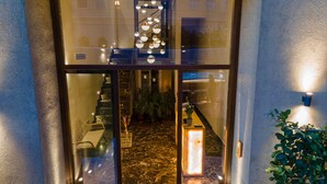 Una entrada moderna con puerta de cristal, suelo de mármol y una escalera que da acceso al interior.