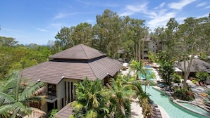 Ein Resort mit Pool, Palmen und einem großzügigen Gebäude mit geneigtem Dach.