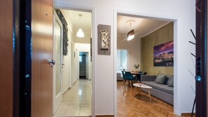 A modern living room with a sofa, a dining table, and a painting on the wall.