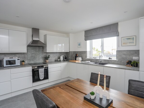 A modern kitchen with white cabinets, a built-in oven, a microwave, and a large window with a view.