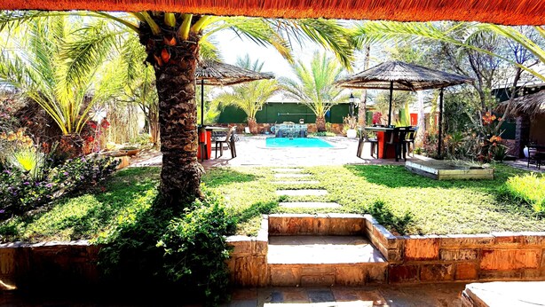 A garden with a pool, palm trees, and outdoor seating areas. - Bethanie Hotel and Guesthouse (Bethanie)
