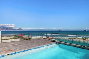 Ein Poolbereich mit Blick auf das Meer und einen entfernten Berg.