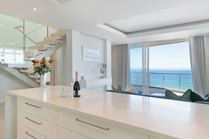 A modern kitchen with a view of the sea, a staircase, and a dining area with a view. - Horizon Bay 1602 Penthouse Apt with lovely views (Cape Town)