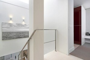 Ein modernes Interieur mit einer Treppe, einem Gemälde und einer roten Tür.