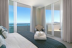 Ein Hotelzimmer mit Bett, Stuhl, Meerblick und einem Balkon.