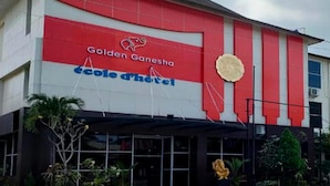 The exterior of the Golden Ganesha Ecole d'Hotel with a prominent red and white facade and a large emblem above the entrance. - Golden Ganesha Hotel Yogyakarta by Ecommerceloka (Banguntapan)