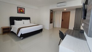 A modern hotel room with a large bed, a desk, and a television. - Golden Ganesha Hotel Yogyakarta by Ecommerceloka (Banguntapan)