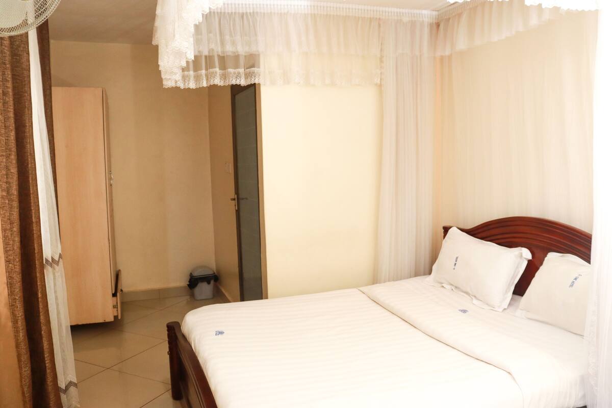 A bedroom with a bed, wooden headboard, and a wardrobe.