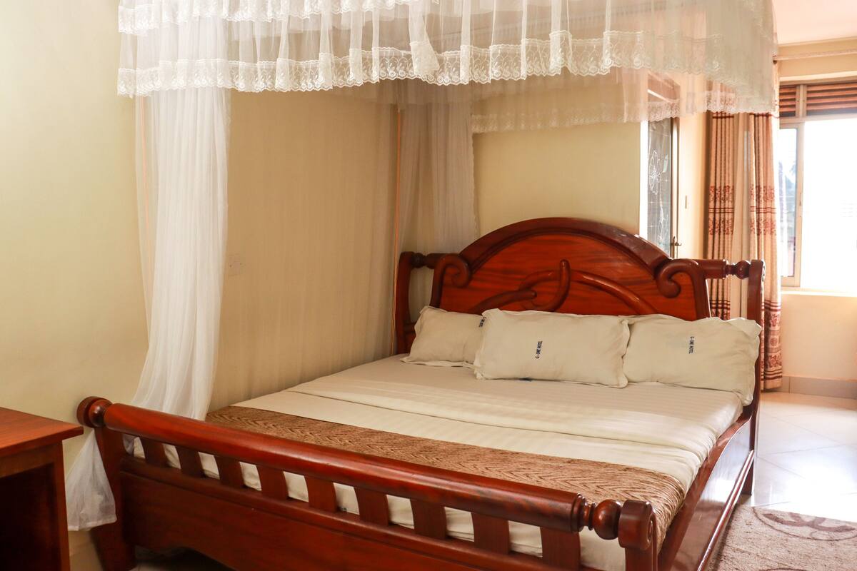 A wooden bed with a canopy, white bedding, and a bedside table.