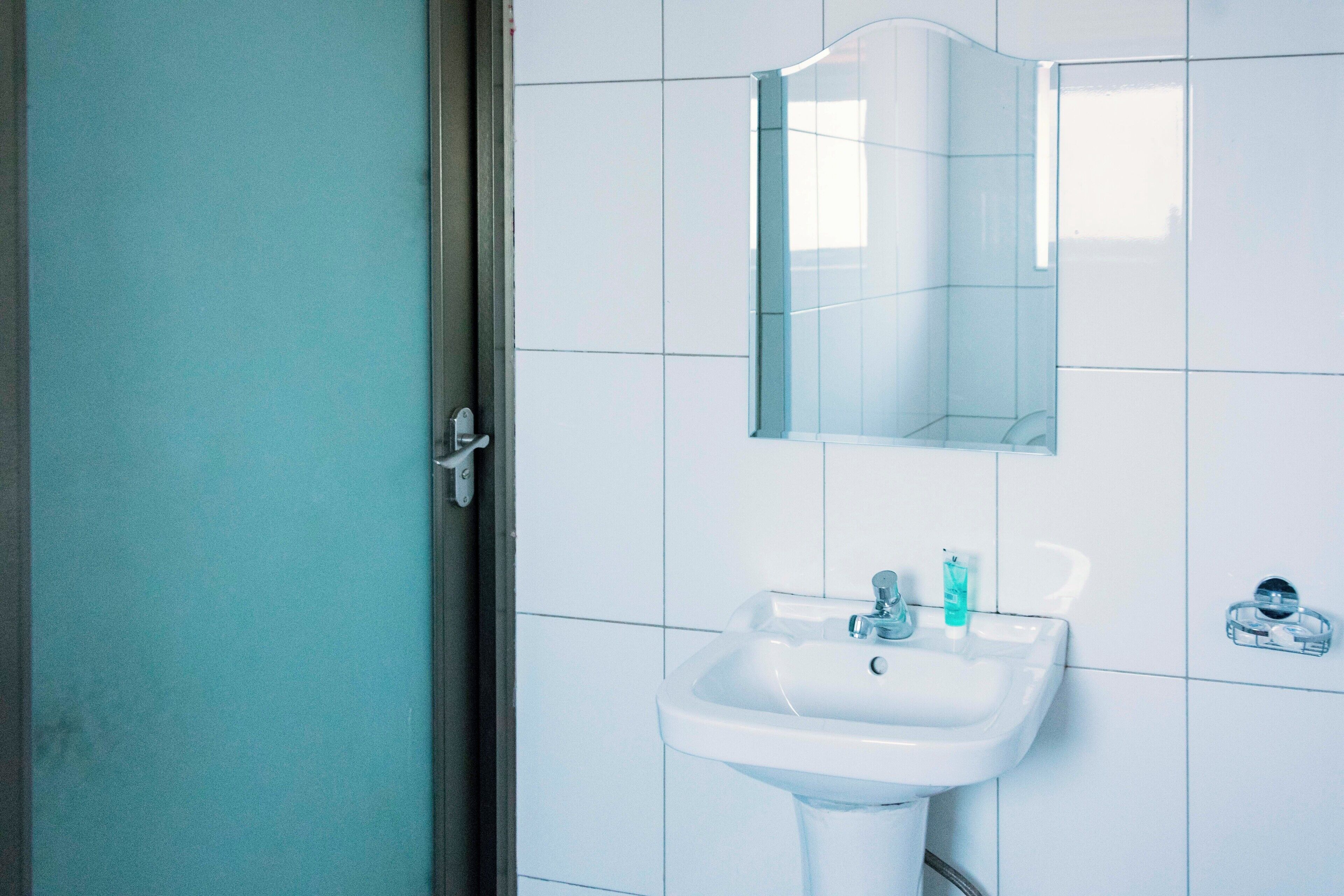 Un baño con lavamanos blanco, espejo y cabina de ducha de vidrio.