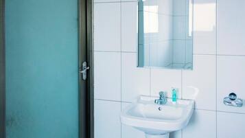Un baño con lavamanos blanco, espejo y cabina de ducha de vidrio.