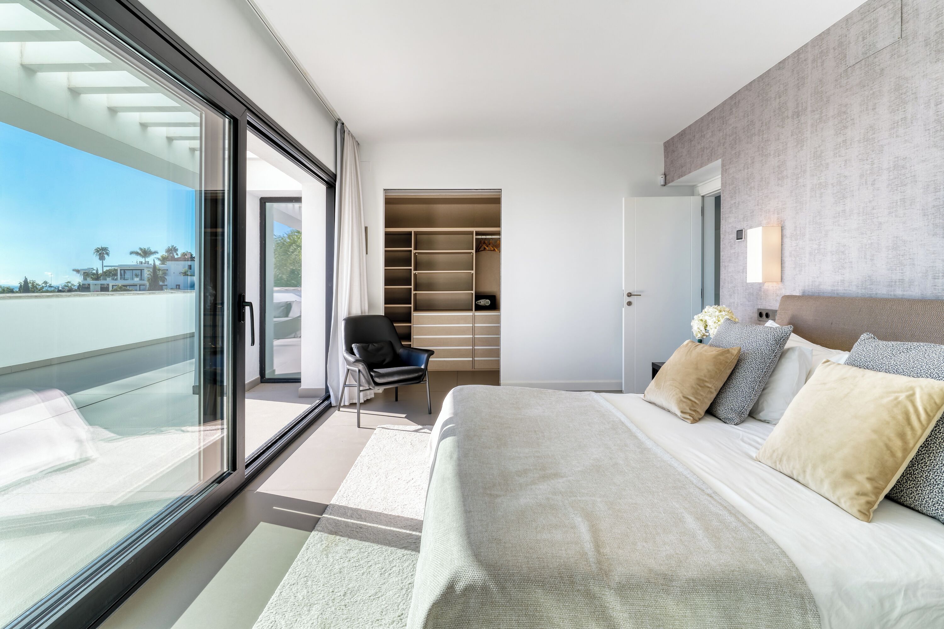 A modern hotel room with a large bed, a walk-in closet, and a view of the ocean.