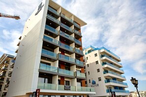 A multi-story hotel with balconies, a sign indicating it is a 'Parador', and a construction crane in the background. - Apartamente 2 Tomis Villa (Navodari)
