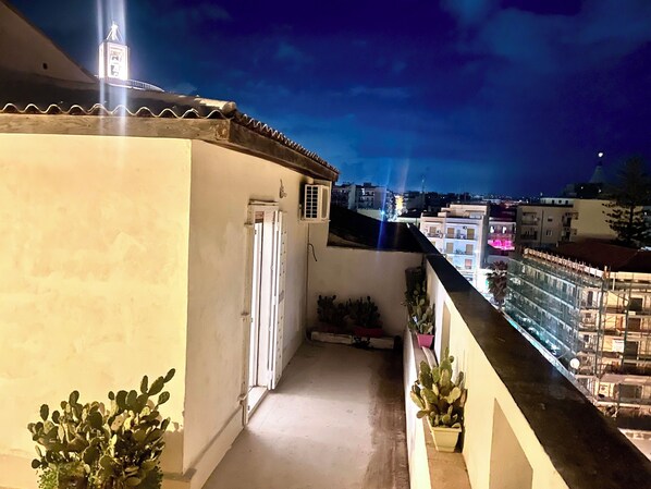 Un balcón con vistas a edificios y una torre al fondo.