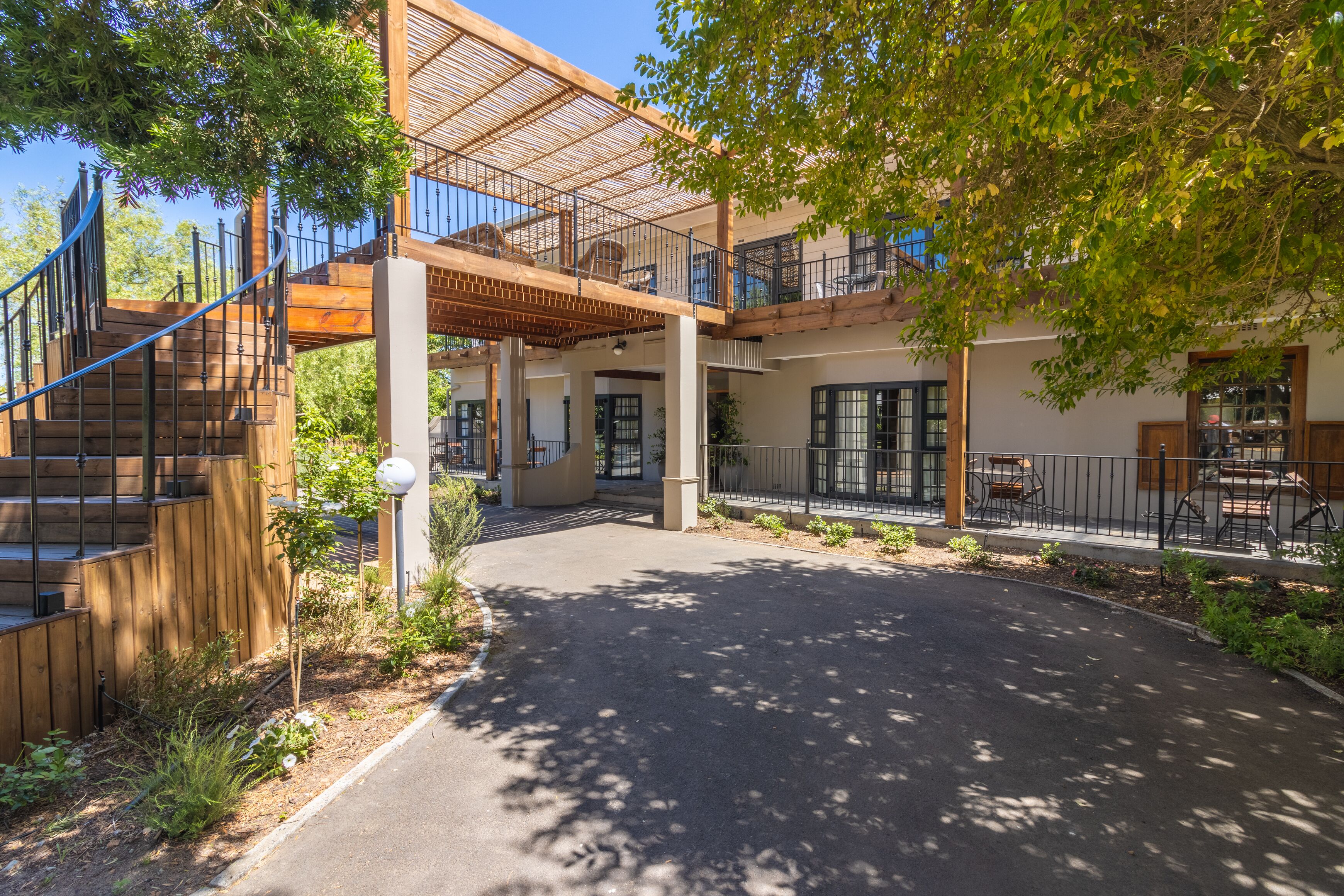 A modern building with a covered outdoor area, wooden steps, and a paved entrance.