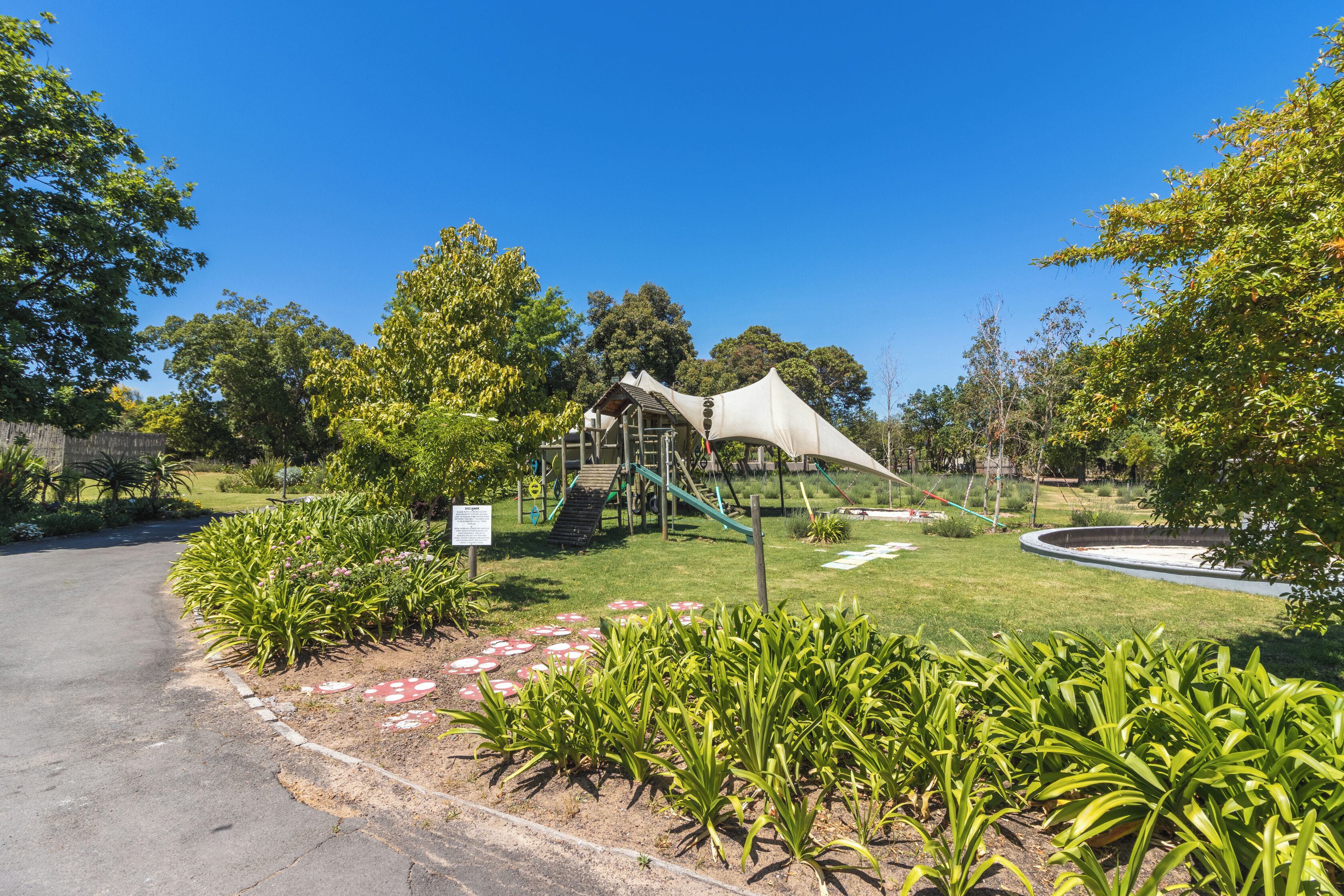A park with a playground, a covered area, and a circular garden.