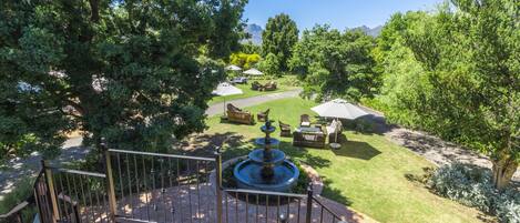 A deck with a fountain, surrounded by a well-maintained lawn and outdoor furniture.