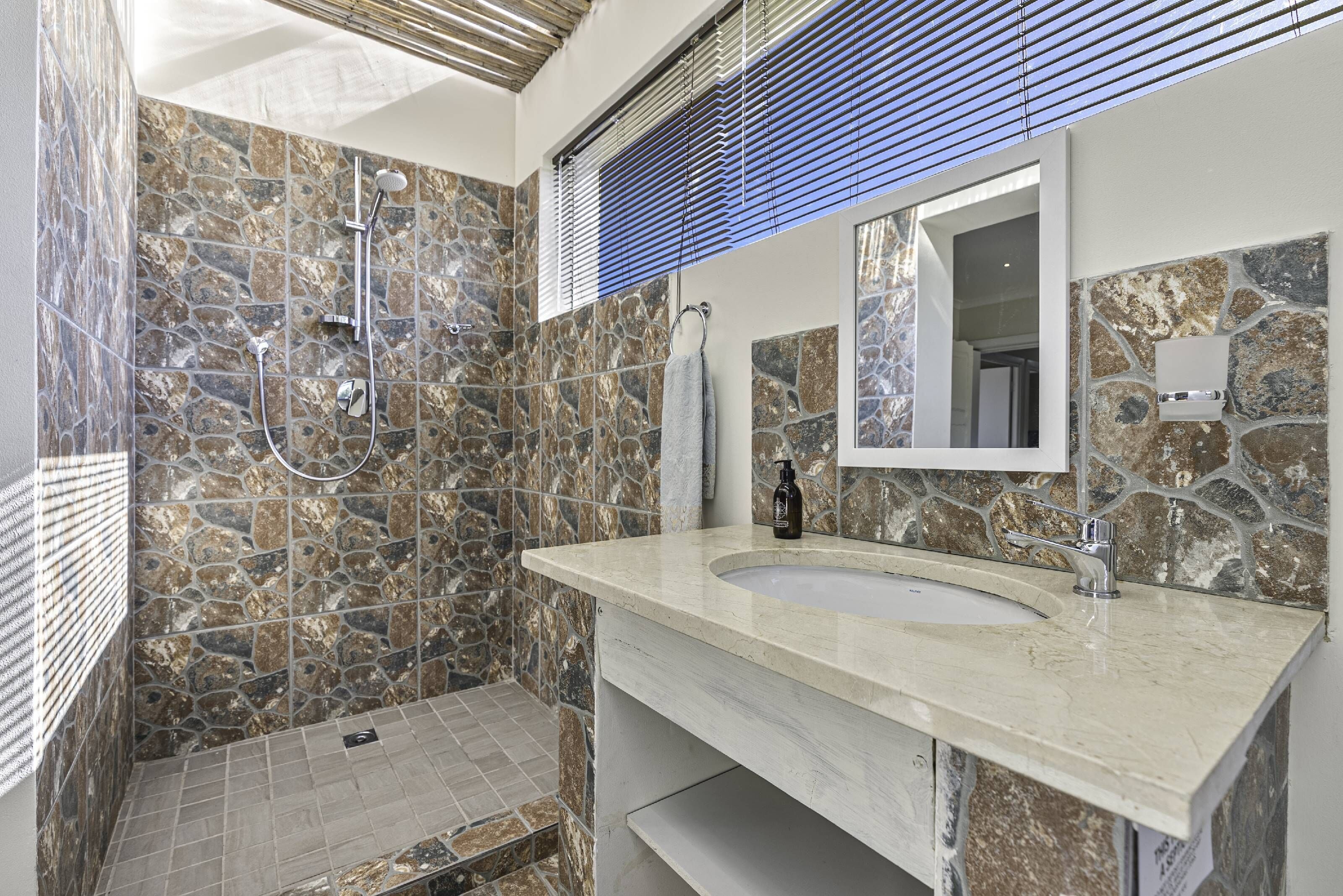 Une salle de bain avec un mur en pierre, un lavabo et une douche.