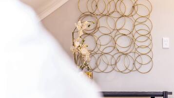 A wall with a gold circular metal art piece and a small white flower arrangement.