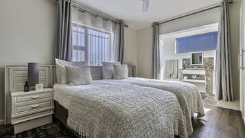 A double bed with a white headboard, a bedside table with a lamp, and a view of the bathroom through an open door.
