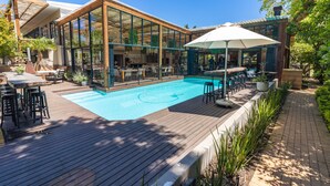 Un espace aménagé au bord de la piscine, avec des sièges d’extérieur, une piscine et un patio couvert.