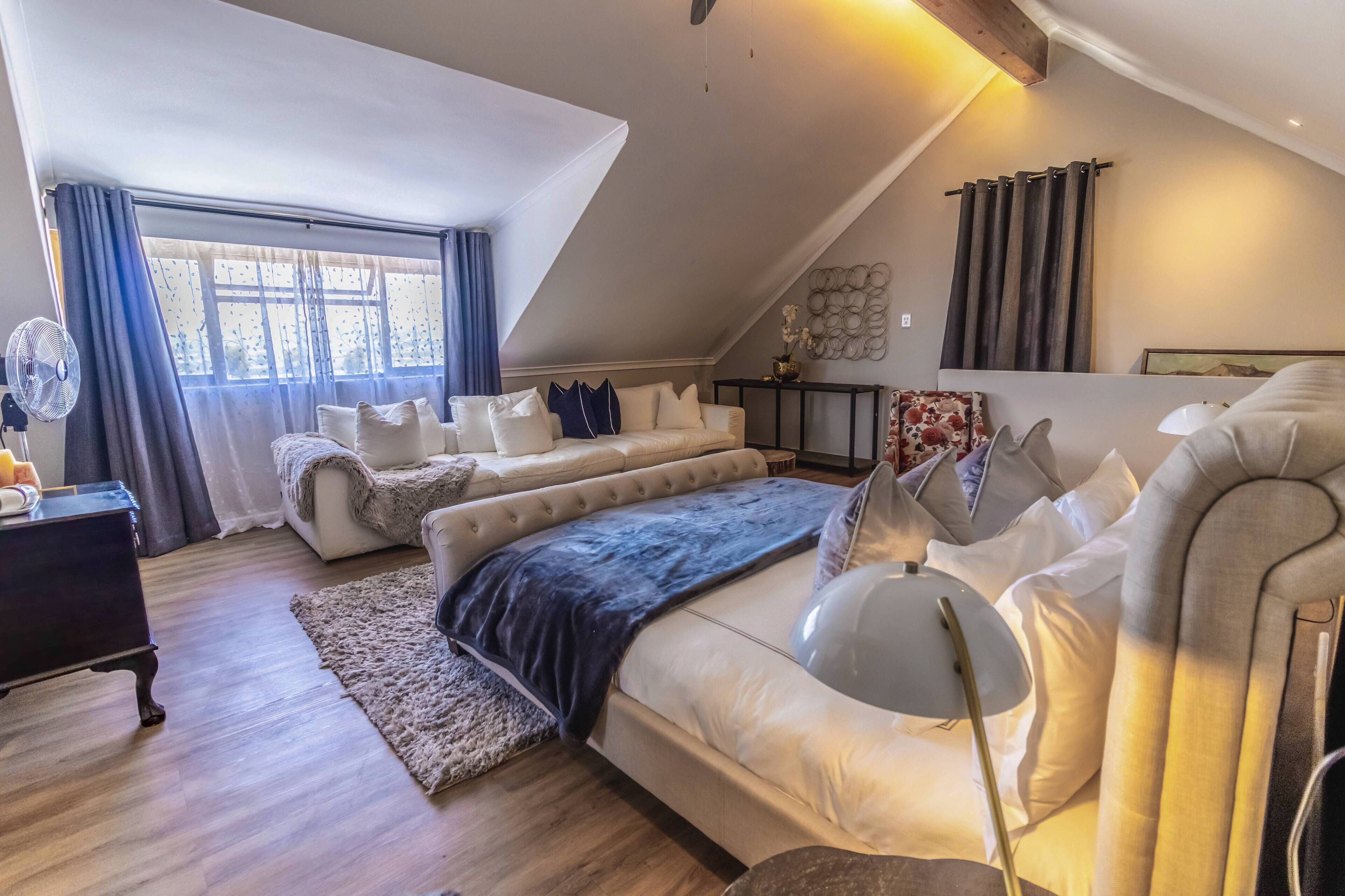 A modern bedroom with a large bed, a sofa, and a desk.
