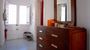Una habitación con tocador de madera, espejo y zapatero.
