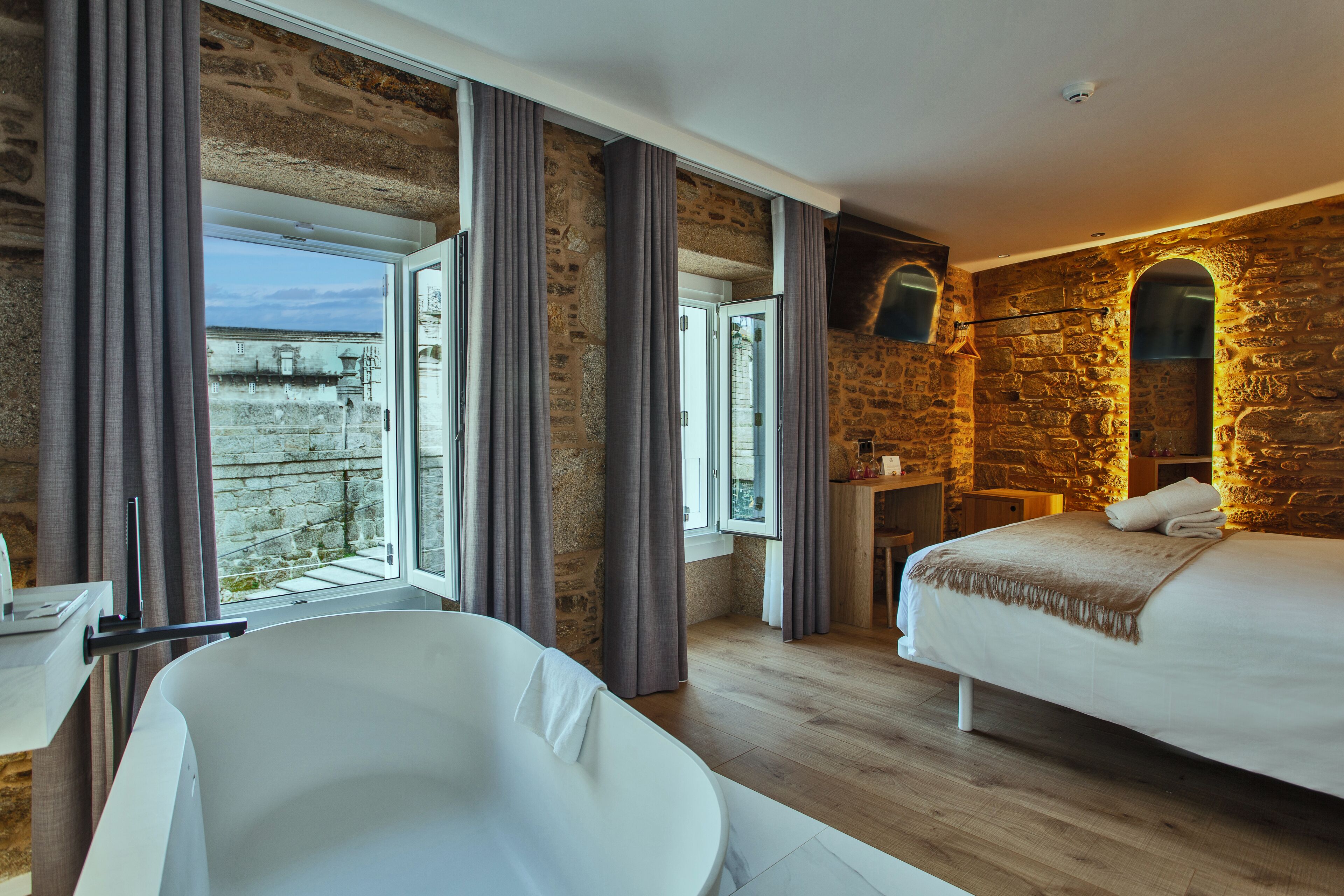 Een moderne slaapkamer met een groot bed, een badkuip en een stenen muur.