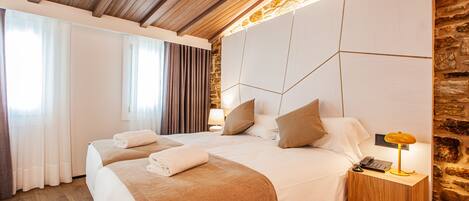 Habitación de hotel con dos camas, techo de madera, pared de piedra y una mesita de noche con lámpara.