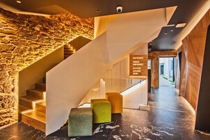 Un moderno vestíbulo de hotel con una pared de piedra, una escalera de madera y un mostrador de recepción.