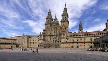 A historic square with a prominent cathedral featuring twin towers and a bell tower.