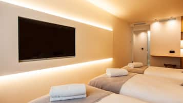 Ein Hotelzimmer mit zwei Betten, einem an der Wand befestigten Flachbildfernseher und einem Spiegel über den Betten.