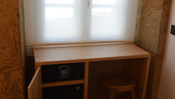 Ein kleiner Holztisch mit Hocker, ein kleines Schränkchen und ein Fenster mit Jalousien.