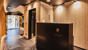 A modern reception area with a wooden finish, a reception desk, and an elevator. -  Hotel Plaza Obradoiro by Bossh! Hotels (Santiago de Compostela)