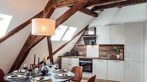 A modern kitchen with white cabinets, a wooden ceiling, and a dining area with a round table set for four.