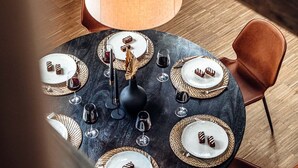 A round dining table with six chairs, a central light fixture, and a modern chandelier.