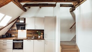 A modern kitchen with white cabinetry, a built-in oven, and a wooden countertop.