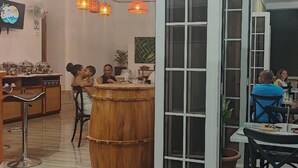 Un interior de restaurante con una barra de madera, lámparas colgantes anaranjadas y un televisor en la pared.