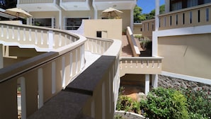 Un hotel de varios pisos con un balcón curvo, asientos exteriores y una escalera que conduce a los pisos superiores.