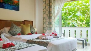 Habitación de hotel con dos camas, un balcón con vistas a zonas verdes y un cuadro en la pared.