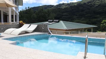 Una piscina al aire libre, sillones reclinables de piscina